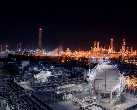 Gas storage sphere tanks and pipeline in oil and gas refinery industrial plant with glitter lighting industry estate at night